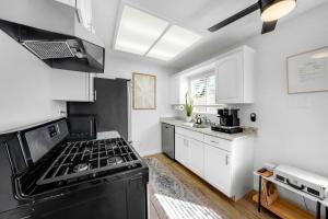 a kitchen with a black stove and white cabinets at Beacons Beach Cottage in Encinitas +22 photos