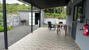 patio ze stołem, krzesłami i sprzętem do grillowania w obiekcie Les Zamours Des Lianes w mieście Saint-Joseph