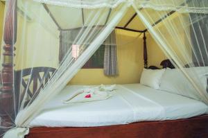 a bedroom with a canopy bed with white sheets at Green Villa in Kahawa