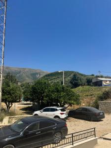Dos coches estacionados en un estacionamiento con montañas al fondo. en Vlore Radhimë Vacation Home, en Vlorë