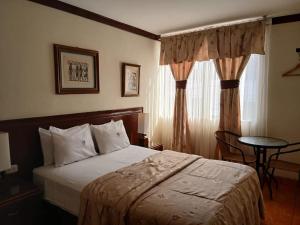 a bedroom with a bed and a table and a window at Hospedaje El Escudero in Trujillo