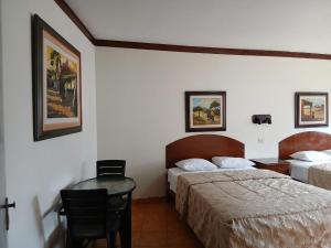 a hotel room with two beds and a table and chairs at Hospedaje El Escudero in Trujillo