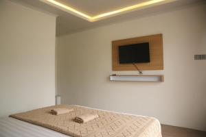 a bedroom with a bed and a flat screen tv at Swarga Rinjani in Sembalun Lawang