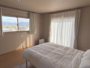 a bedroom with a bed and a large window at Cozy House Azumino in Azumino