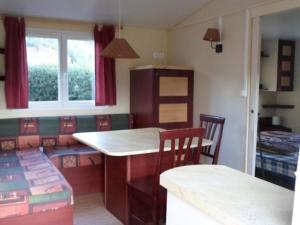 a kitchen with a counter and a table and chairs at Mobil-home 6 personnes avec terrasse à La Chapelle-devant-Bruyères - API-1-52-1002 in La Chapelle