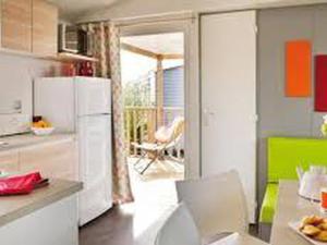 a kitchen with a white refrigerator and a dining table at Mobil-home 38m² avec terrasse pour 6 personnes - API-1-52-1008 in Luynes