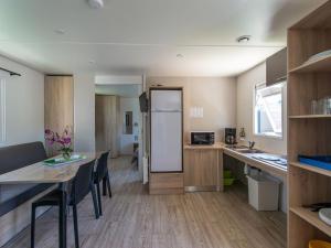 una cocina y comedor con una mesa y un refrigerador en Mobil-home PMR avec Terrasse à Saint-Rome-de-Tarn - API-1-52-1012, en Saint-Rome-de-Tarn