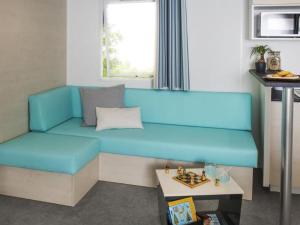 ein blaues Sofa in einem Zimmer mit einem Tisch in der Unterkunft Mobil home confortable avec terrasse - API-1-52-1015 in Port Blanc
