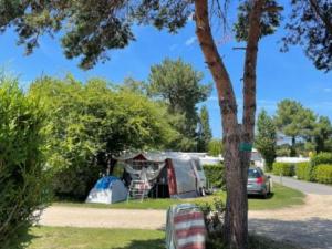 ein Zelt und ein Auto, die neben einem Baum geparkt sind in der Unterkunft Mobil home confortable avec terrasse - API-1-52-1015 in Port Blanc