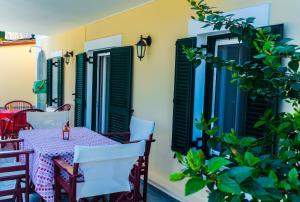 a table and chairs on a patio with green shutters at Dionos Villa in Asos