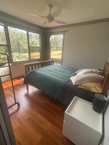 a bedroom with a bed with a fan and windows at Quiet Rural Retreat - Kimbriki in Mount George