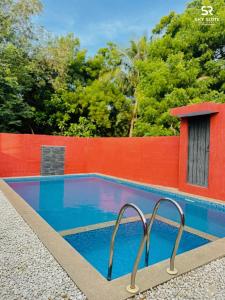 a swimming pool with a red fence and a blue at sky suite residency in Auroville