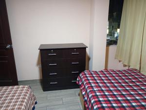 a bedroom with a dresser and a bed with a plaid blanket at Departamento AQP in Arequipa