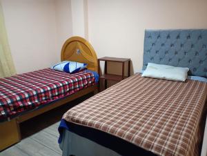 a bedroom with two beds and a blue headboard at Departamento AQP in Arequipa
