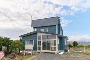 a blue house with a black roof at Casa Katatsumuri in Nakafurano