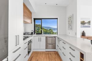 eine Küche mit weißen Schränken und einem Fenster in der Unterkunft Vista Serena in Pohara