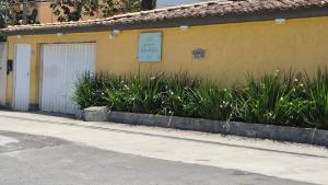 リオデジャネイロにあるLoft aconchegante na praia do Recreioの白い扉と植物のある黄色い建物