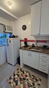 リオデジャネイロにあるLoft aconchegante na praia do Recreioの白いキャビネットと黒と白のラグ付きのキッチン