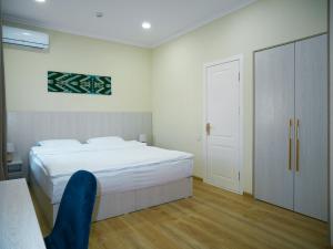a bedroom with a white bed and a blue chair at Oasis Boutique in Bukhara