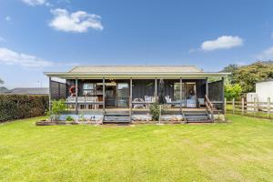 a house with a large lawn in front of it at Hosts on the Coast Paws & Relax Bach in Hahei
