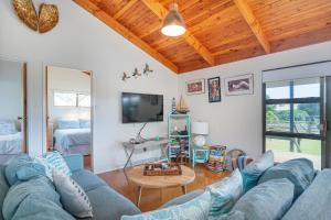 a living room with a blue couch and a tv at Hosts on the Coast Paws & Relax Bach in Hahei