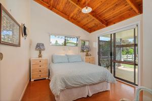 a bedroom with a bed and a window at Hosts on the Coast Paws & Relax Bach in Hahei
