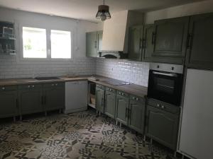 eine Küche mit grünen Schränken und Fliesenboden in der Unterkunft Maison By Medoc in Bégadan