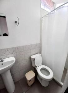 een witte badkamer met een toilet en een wastafel bij Casa Hospedaje Sunya in Cuzco