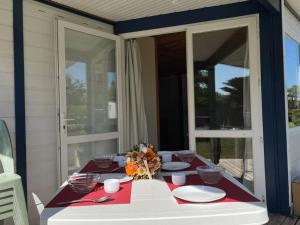 einen Tisch mit Tellern und Blumen auf einer Veranda in der Unterkunft Chalet 5 pers - PMR - Terrasse spacieuse - API-1-52-1017 in Dolus d'Oléron