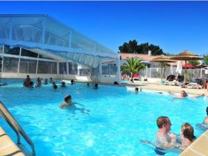 eine Gruppe von Menschen, die in einem Schwimmbecken schwimmen in der Unterkunft Chalet 5 pers - PMR - Terrasse spacieuse - API-1-52-1017 in Dolus d'Oléron