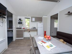 Una cocina y un comedor con mesa y sillas. en Mobil-home PMR avec Terrasse à Hyères - API-1-52-1030, en La Decapris