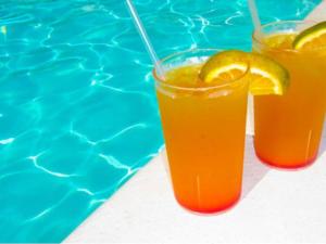 two glasses of orange juice next to a swimming pool at Chalet de 28m² pour 4 personnes avec terrasse - API-1-52-1035 in Garindein +21 photos