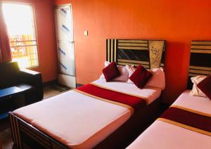 Sumeru Hotel and Lodge في Itahari: سريرين في غرفة بجدران برتقالية +7 صور