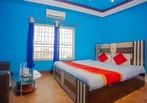 Sumeru Hotel and Lodge في Itahari: غرفة نوم بجدران زرقاء وسرير بمخدات حمراء