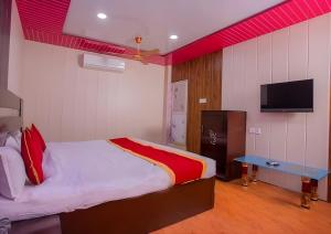 Sumeru Hotel and Lodge في Itahari: غرفة نوم مع سرير وتلفزيون بشاشة مسطحة