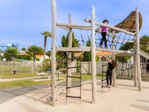 Zwei Kinder schaukeln auf einer Seilschaukel auf einem Spielplatz in der Unterkunft Mobil Home Prestige avec Terrasse à Saint-Jean-de-Monts - API-1-52-1055 in Notre-Dame-de-Monts