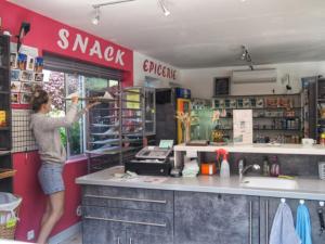 a woman is opening a window of a shop at Mobil-home cosy avec terrasse pour 5 personnes - API-1-52-1066 in Saint-Rome-de-Tarn +13 photos
