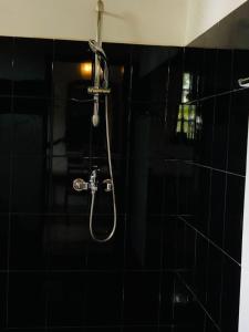 a shower in a bathroom with a black tiled wall at Borala Lake Weligama in Weligama