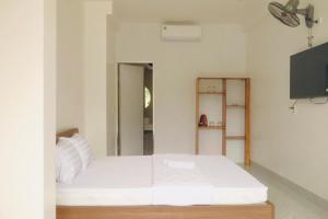 a bedroom with a white bed and a flat screen tv at Hiên's Homestay in Hue