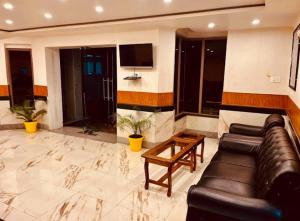 a living room with a leather couch and a tv at MGallery Hotel in Srinagar