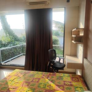 ein Schlafzimmer mit einem Bett, einem Stuhl und einem Fenster in der Unterkunft Green Courtyard Luxury Villa in Badlapur