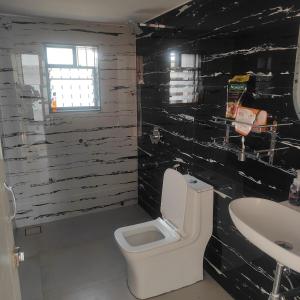 a bathroom with a white toilet and a sink at Green Courtyard Luxury Villa in Badlapur