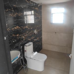 ein Badezimmer mit einem weißen WC und einer schwarzen Wand in der Unterkunft Green Courtyard Luxury Villa in Badlapur