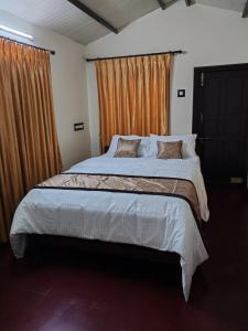 a bedroom with a large bed with orange curtains at The Sparrow House 1BHK First Floor in Kumbakonam