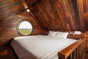 a bed in a wooden room with a round window at An House in Sóc Sơn