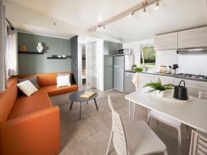 a living room with an orange couch and a table at Mobil-home confortable avec terrasse - API-1-52-1100 in Luynes