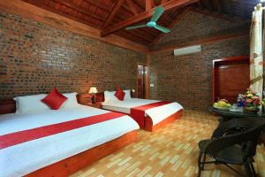 Un dormitorio con dos camas y una pared de ladrillo. en TAM FAMILY HOMESTAY and RESTAURANT, en Ninh Binh