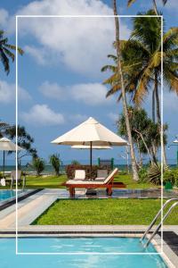 a pool with an umbrella and a bench next to the ocean at Borala Lake Weligama in Weligama