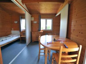a dining room with a wooden table and a bed at Chalet confortable avec terrasse - API-1-52-1104 in Charmes-sur-lʼHerbasse
