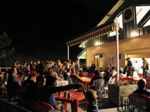 a crowd of people sitting outside a building at night at Chalet confortable avec terrasse - API-1-52-1104 in Charmes-sur-lʼHerbasse